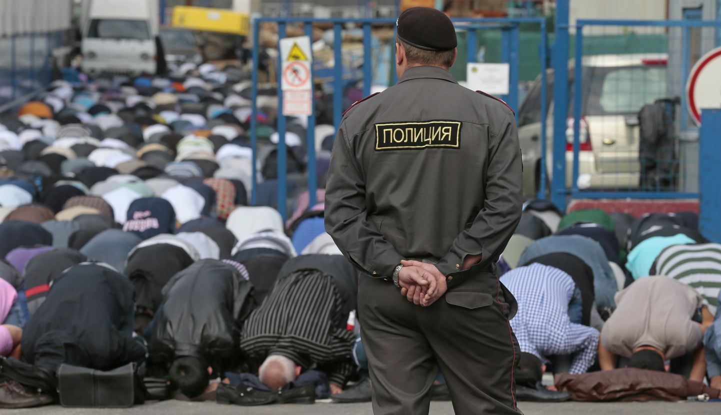 Vene politseinik palvetavaid moslemeid valvamas.
