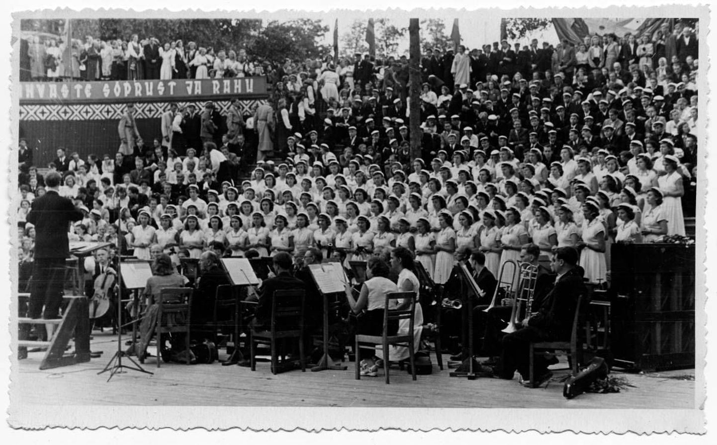 Esimene üliõpilaslaulupidu Tartus 1956. aasta 8. juulil. Esineb TRÜ naiskoor. Dirigeerib Igor Graps. Keskel musitseerivad ülikooli sümfooniaorkestri koosseisus Alo Ritsing ja Udo Kolk.