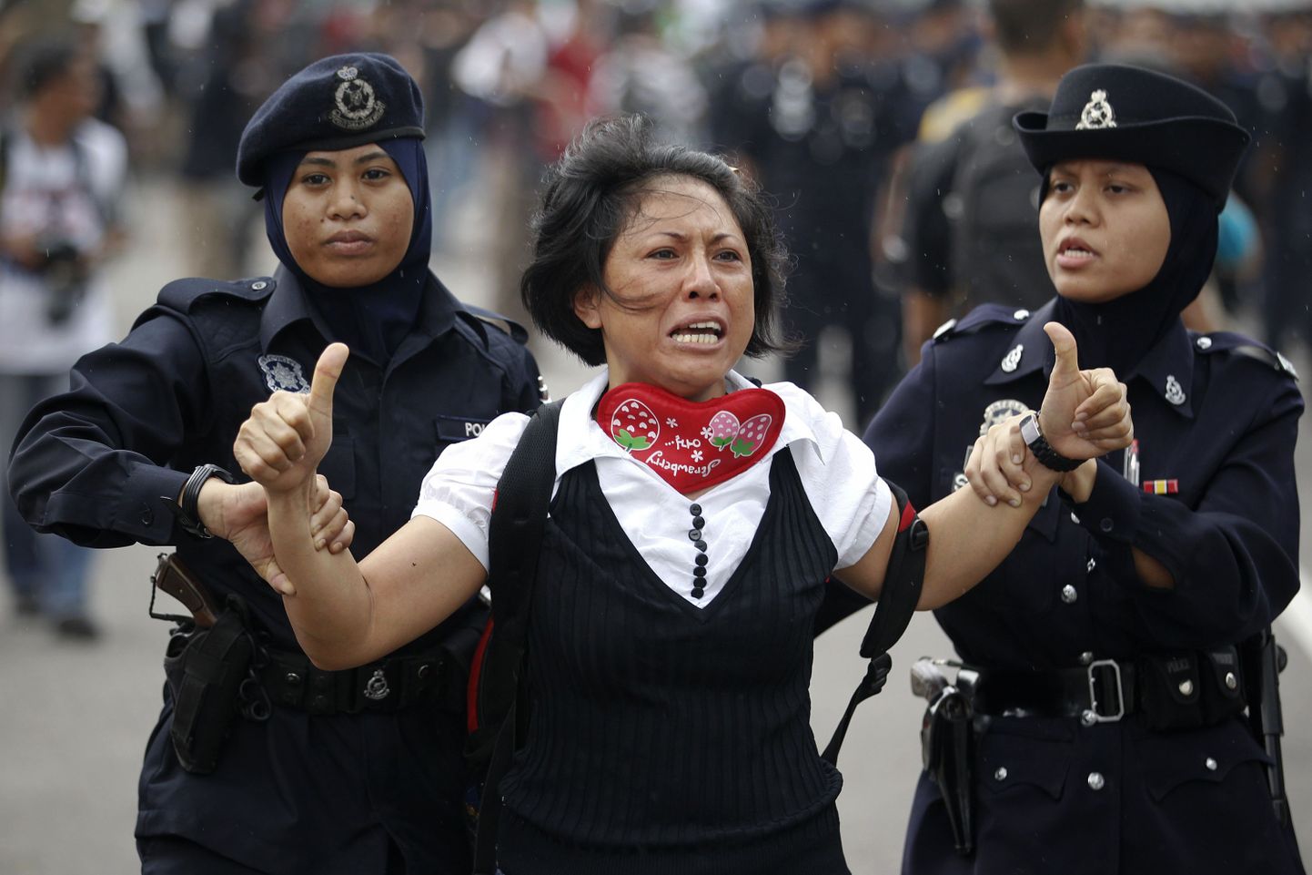 Malaisia politseinikud naissoost meeleavaldajat kinni pidamas.