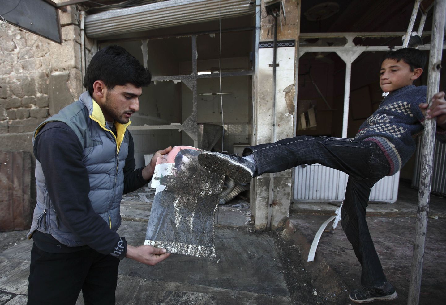 Poiss Sermeeni linnas Põhja-Süürias lööb jalaga president Bashar al-Assadi portreed.