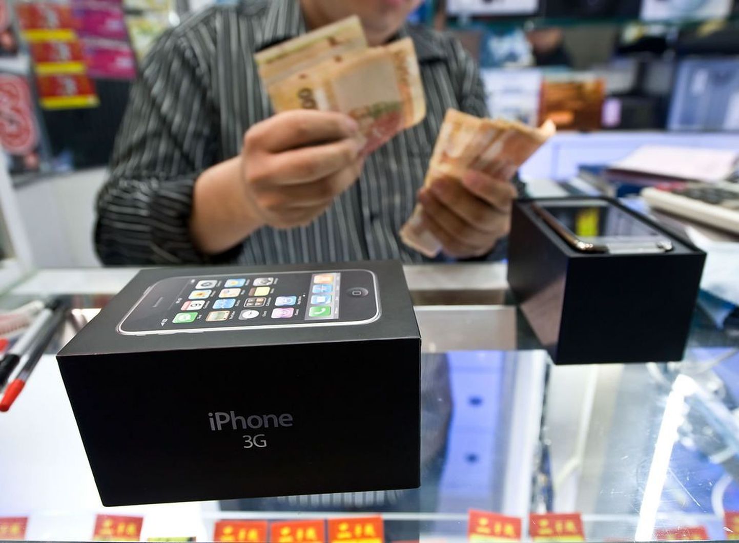 Pildil loeb raha uute iPhone`idega mustal turul kaubitsev Hong Kongi poemüüja.
