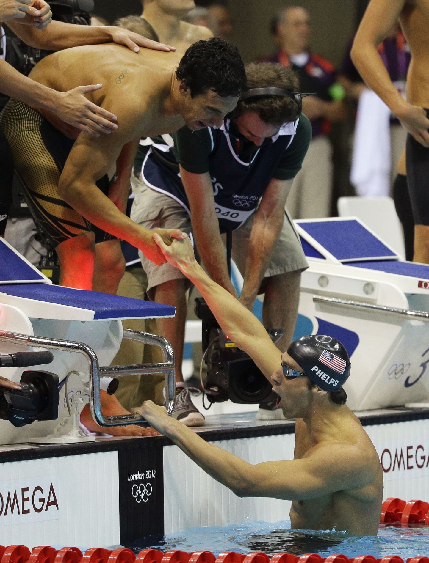 Meeskonnakaaslased ankrumees Michael Phelpsi basseinist välja aitamas.
