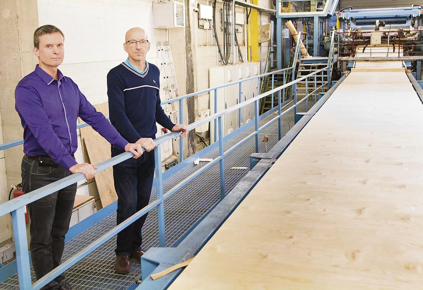 Valmose tegevjuht Heiki Vahermets (vasakul) ja ettevõtte tootmisjuht Mart Põder uue tootmisliini ääres spoonilõikamise protsessi jälgimas.