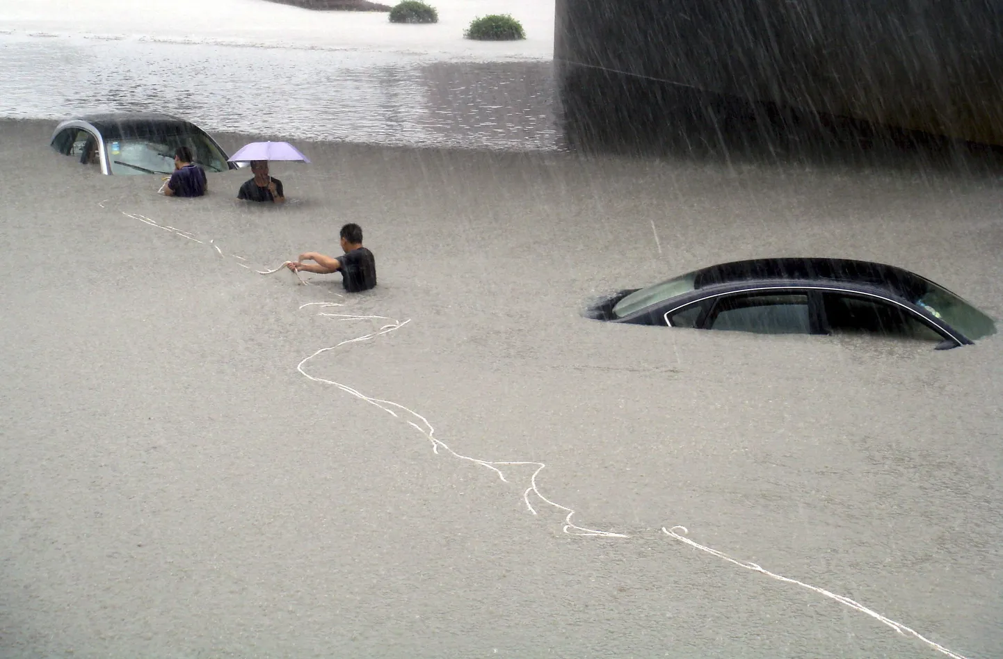 Люди пытаются вытащить автомобиль с затопленной улицы в провинции Фуцзянь.