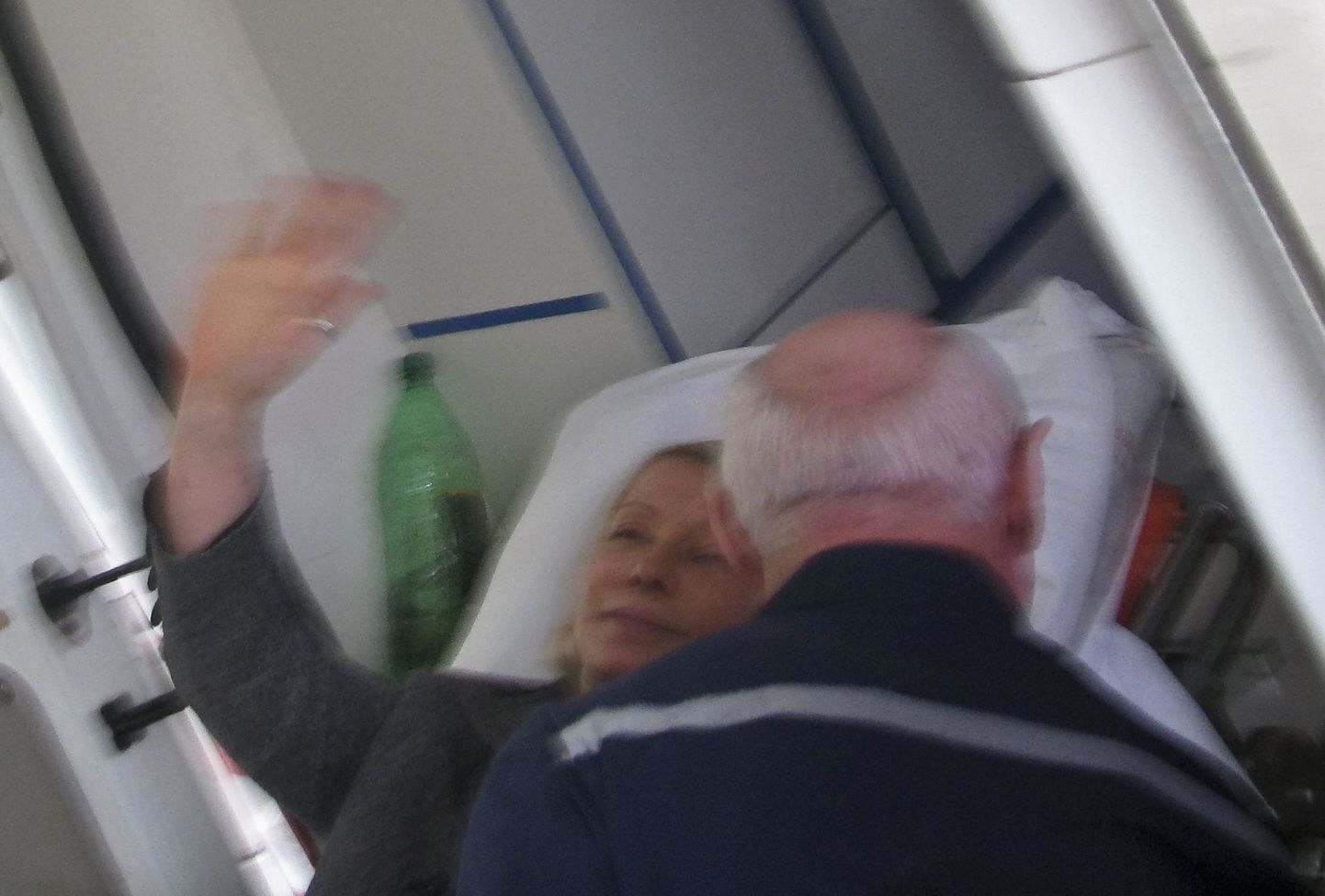 Julia Tõmošenko lehvitab kanderaamil, millega ta sõidutati kiirabiautosse.