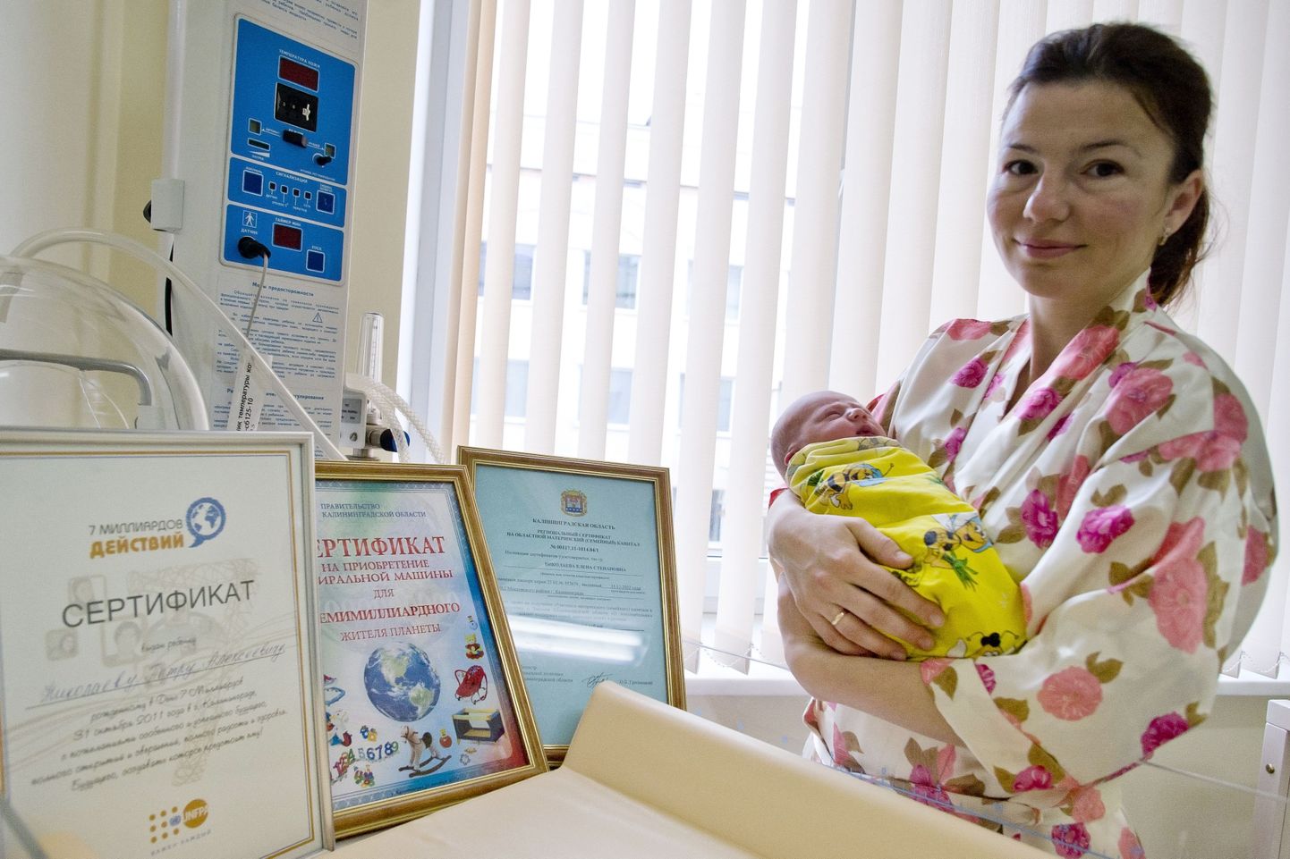 Jelena Nikolajeva koos vastsündinud Pjotriga. Pildil on erinevad sertifikaadid, mille järgi on beebi maailma seitsme miljardendas elanik.