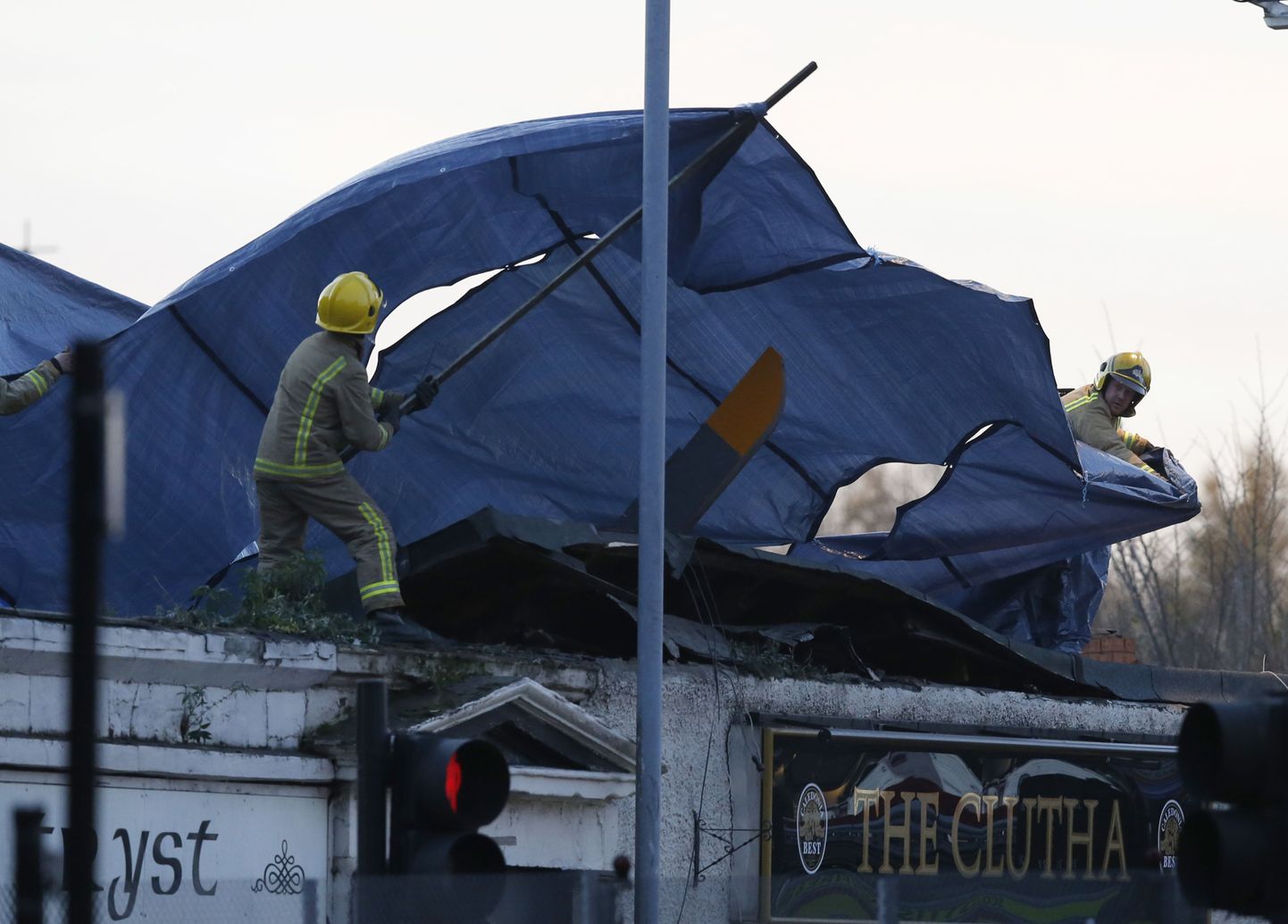 Päästetöötajad katavad Glasgow's pubisse kukkunud kopteri vraki kilega.