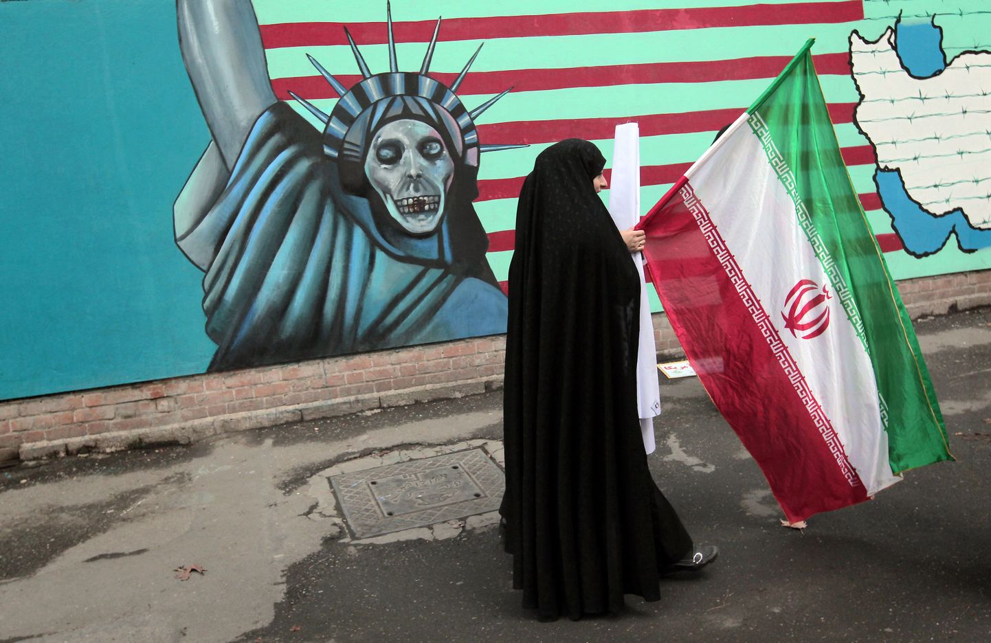 Rahvuslipuga iraanlanna USA-vastase grafiti tausta.