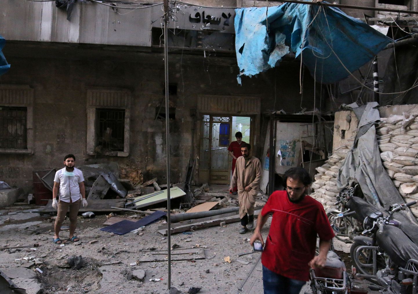 Meedikud üleeile pommitabamuse saanud Aleppo haigla ees.