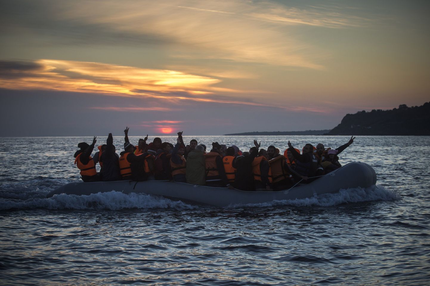 Refugees and migrants calls the attention of a rescue team when approaching the Greek island of Lesbos on a dinghy, after crossing a part of the Aegean sea from Turkey, on Friday, Dec. 25, 2015. The International Organization for Migrants said more than 1 million people have entered Europe earlier this week. Almost all came by sea, while 3,692 drowned in the attempt.(AP Photo/Santi Palacios)