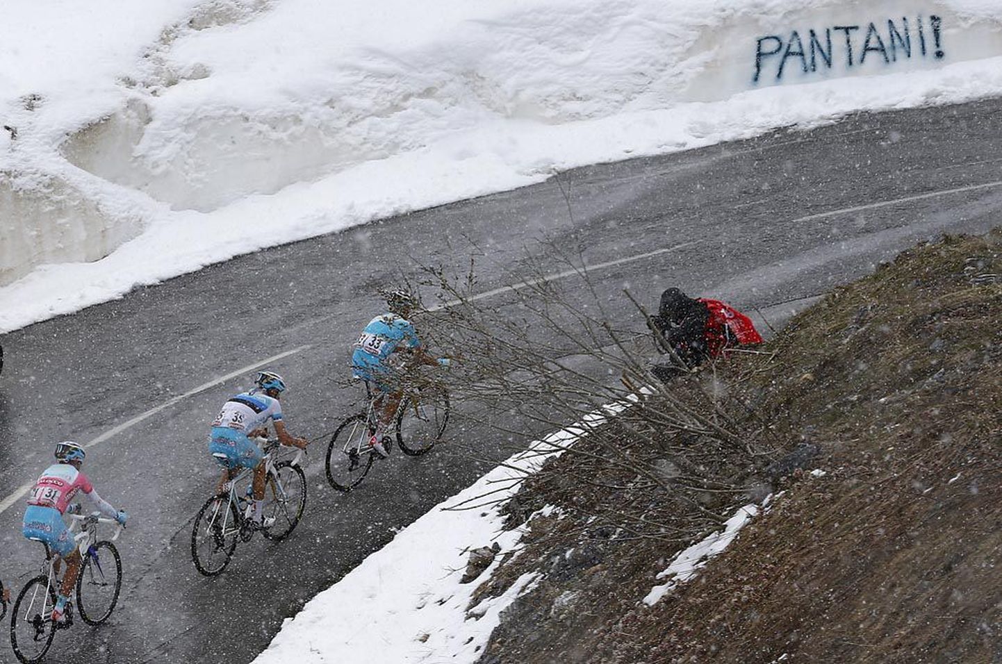Tanel Kangert ees, Astana liider Vincenzo Nibali (roosas särgis, Kangertilt saadud käistega) järel, rühitakse läbi lumesaju.