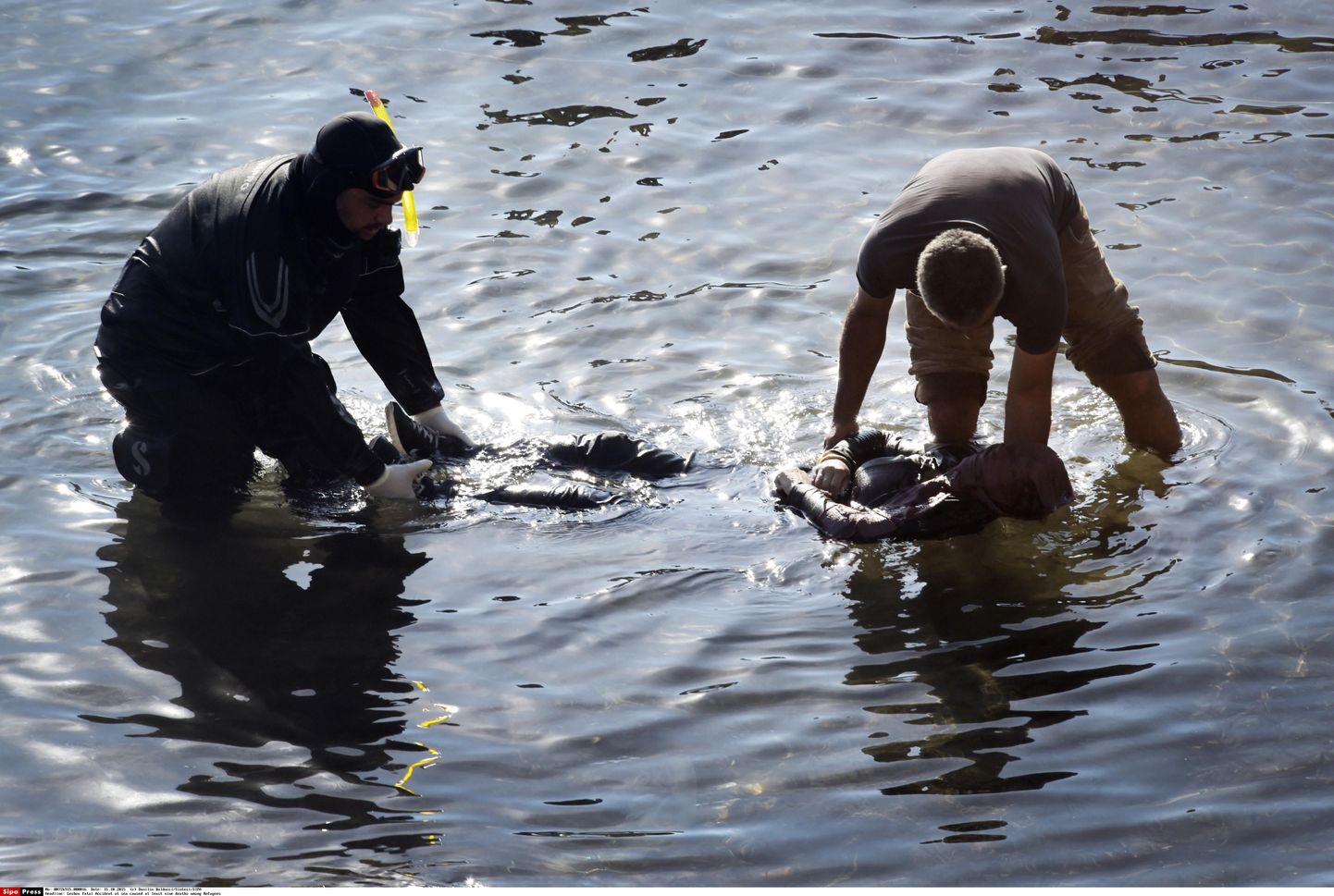 Спасатели достают из воды тела утонувших беженцев.