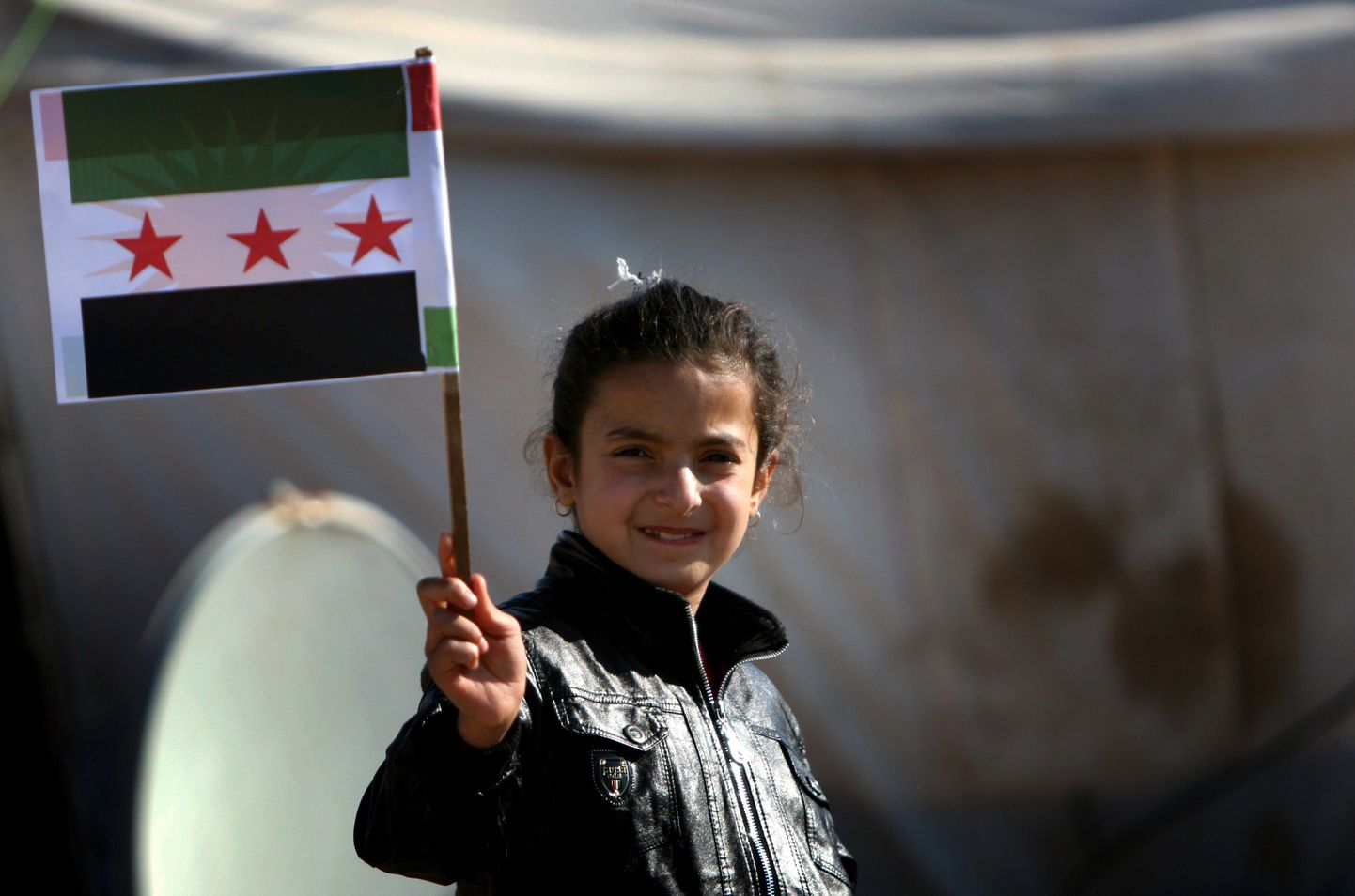 Süüriaa kurdi tüdruk poseerib Iraagis asuvas põgenikelaagris opositsiooni tunnuseks saanud lipuga.