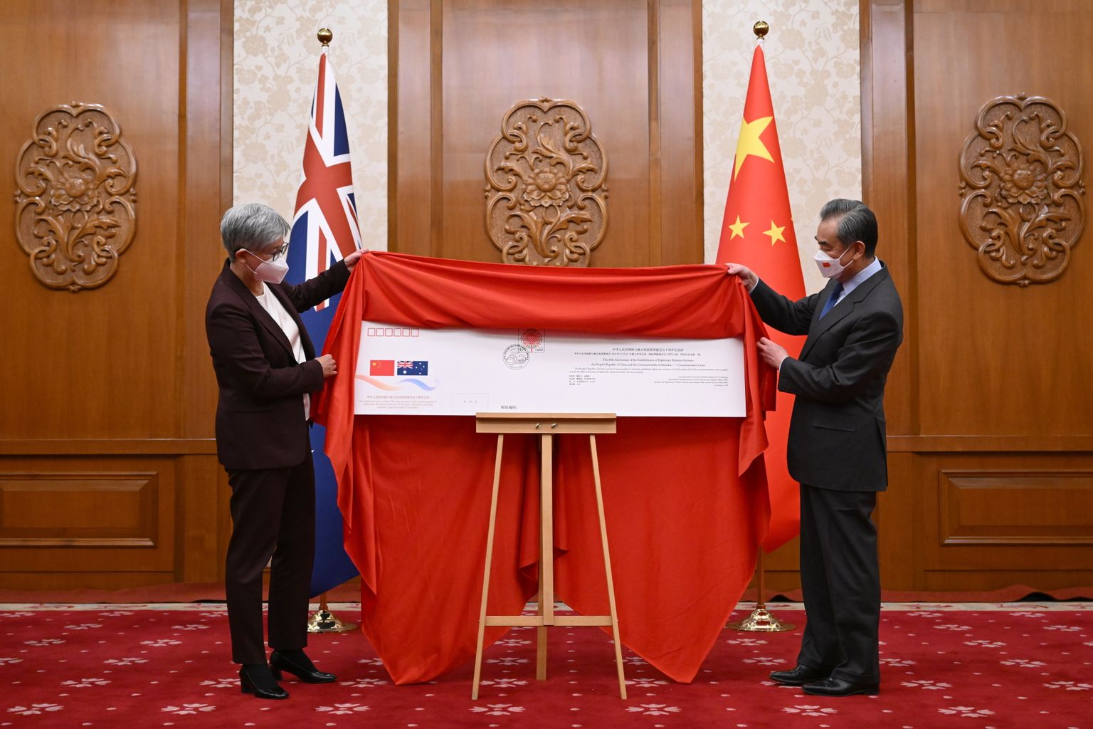 Austraalia välisminister Penny Wong (vasakul) ja tema Hiina kolleeg Wang Yi tõmbavad 21. detsembril Pekingis katte sümboolselt tähtpäevaümbrikult tseremoonial, millega tähistati kahe riigi vaheliste diplomaatiliste suhete loomist 50 aasta eest.