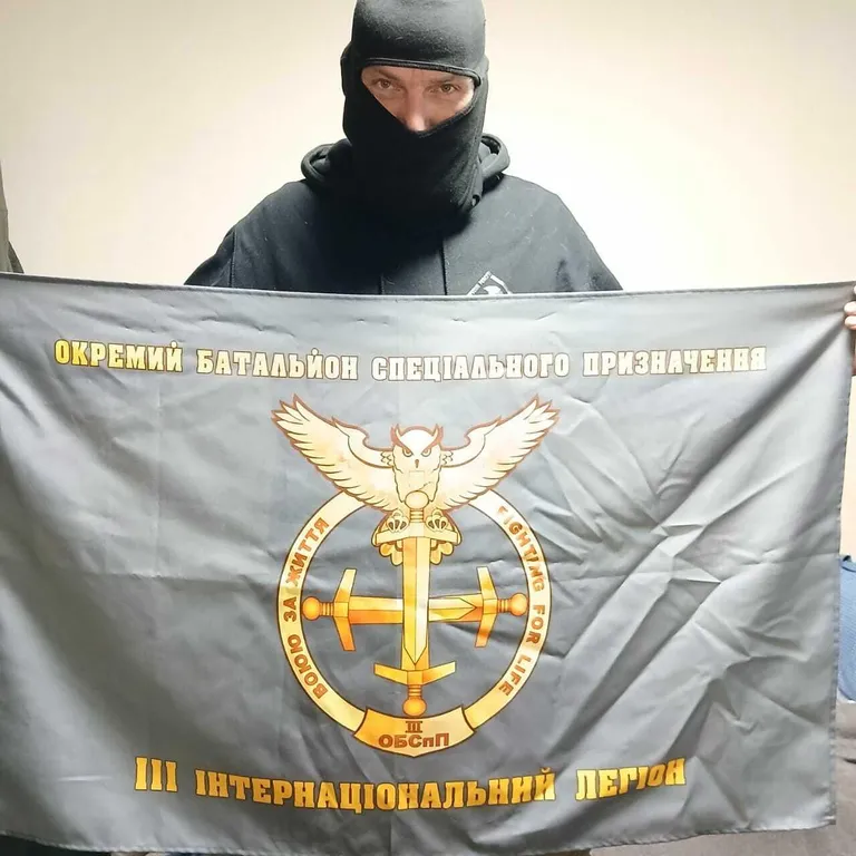 T-Bone держит флаг спецподразделения 3-го Международного легиона Украины.