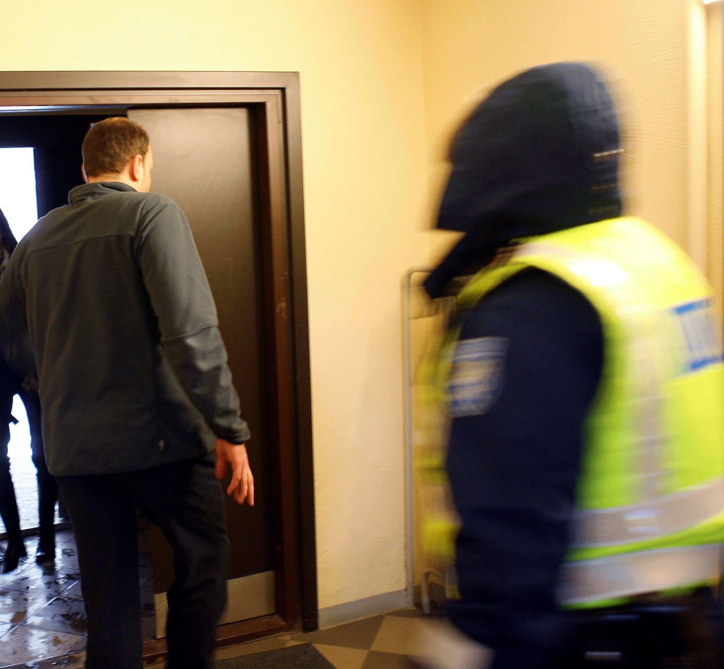 Mitmes süüteos kahtlustatav Andre Ernesaks (seljaga) tänavu märtsi alguses Tallinnas Karu 39 maja trepikojas. Politsei uuris tollal surmajuhtumit Ernesaksa kodukontoris.