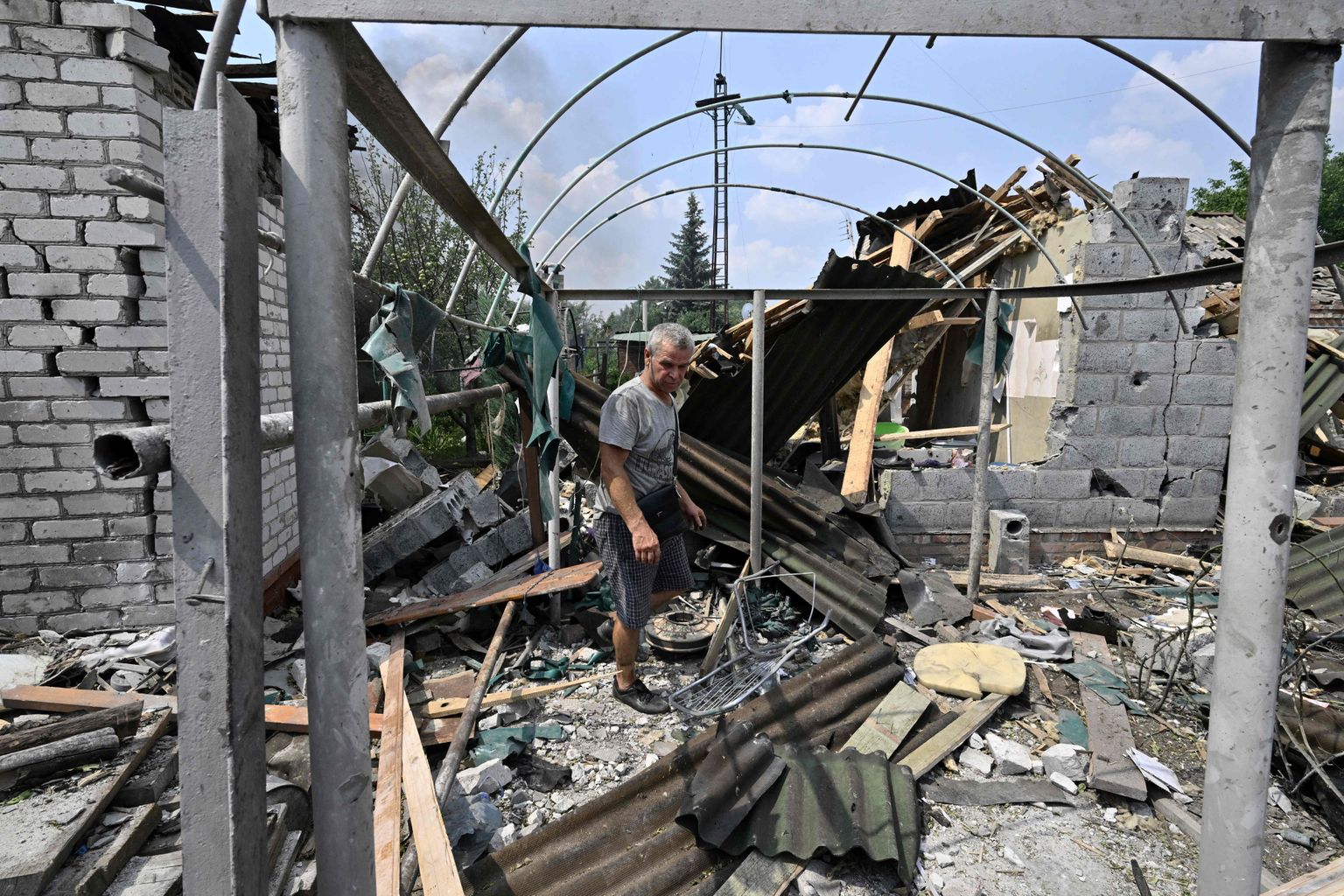 TOPSHOT - A resident walks among debris next to a destroyed house in Sloviansk on July 4, 2022, the day after a Russian rocket attack. (Photo by Genya SAVILOV / AFP)