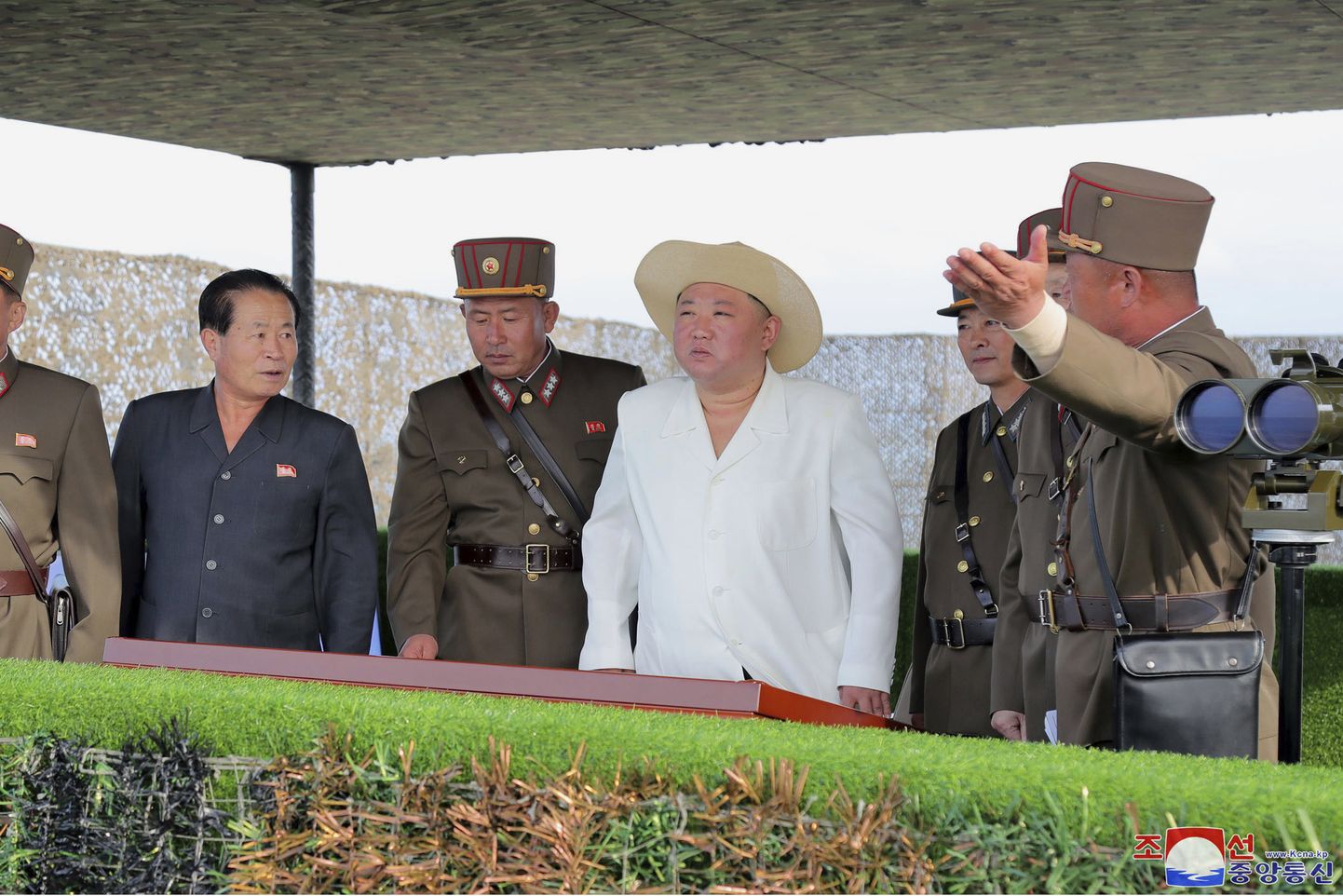 Põhja-Korea liider Kim Jong-un koos kindralitega 6. oktoobril 2022 jälgimas avaldamata paigas raketikatsetust. Teda on näha tavapärase tumeda riietuse asemel heledas ja heleda kaabuga