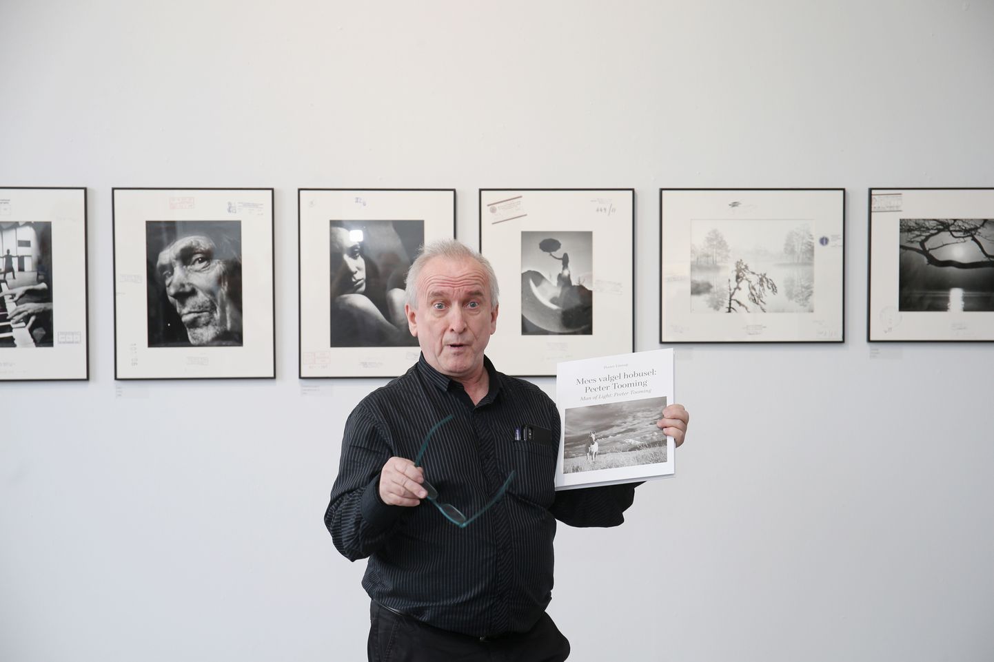 Peeter Linnap rääkis näituse avamisel Peeter Toomingast ja tema fotodest galerii seinal ning hoidis käes enda kirjutatud raamatut.