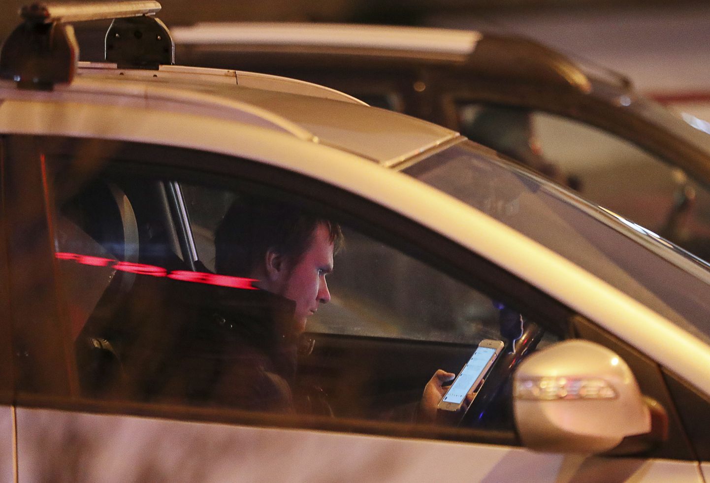Водитель пользуется смартфоном во время поездки.