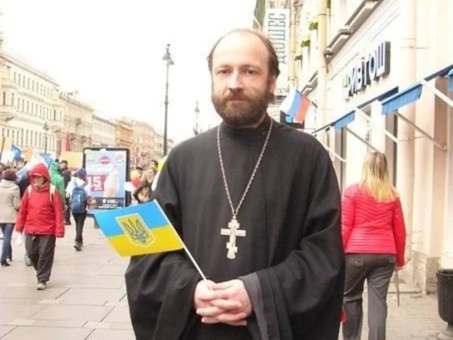 Священник РПЦ Николай Савченко в мае 2014 года на Невском проспекте держит в руках украинский флаг, выражая солидарность с Украиной, на которую уже тогда напала РФ.