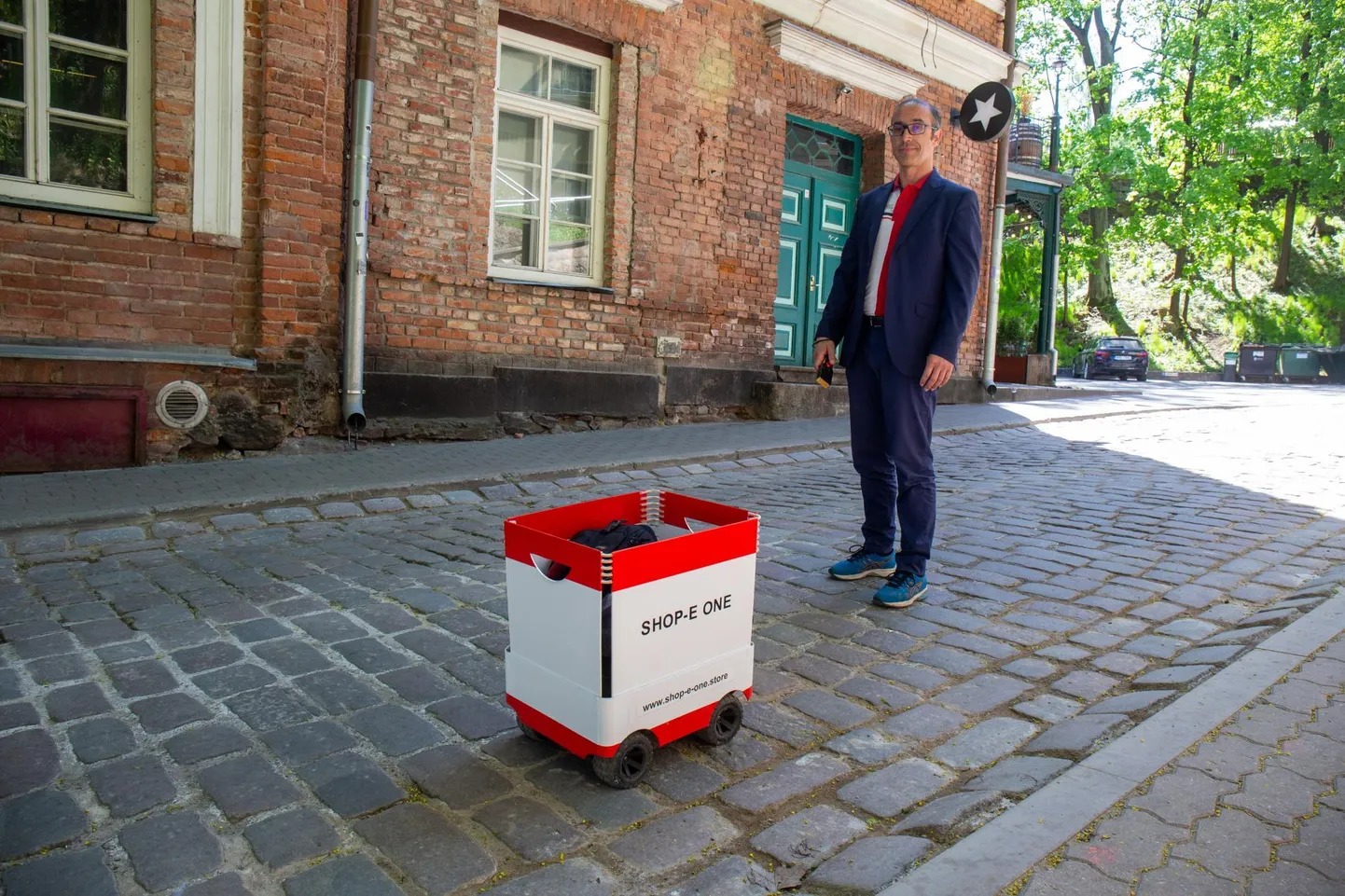Tehnoloogiaettevõtja Marc Wagner katsetamas oma robotkäru Shop-E One Tartus munakivisillutisega Vallikraavi tänaval.