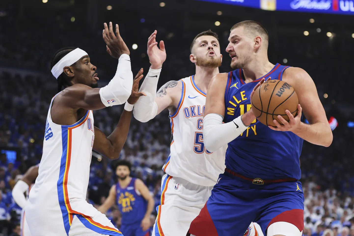 Nikola Jokic (palliga) võitleb rünnakul Oklahoma City Thunderi mängijate Shai Gilgeous-Alexanderi (vasakul) ja Isaiah Hartensteini vastu.