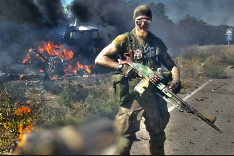 Российский неонацист Ян Петровский, он же "Великий славян", он же Воислав Торден позирует на фоне обгоревшего тела украинского военного.