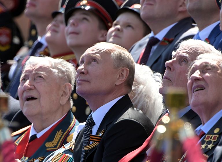 Владимир Путин и ветераны армии всматриваются в небо, где летит российская военная авиация. Красная площадь, Москва, парад в годовщину Победы 1945 года, июнь 2020 года.