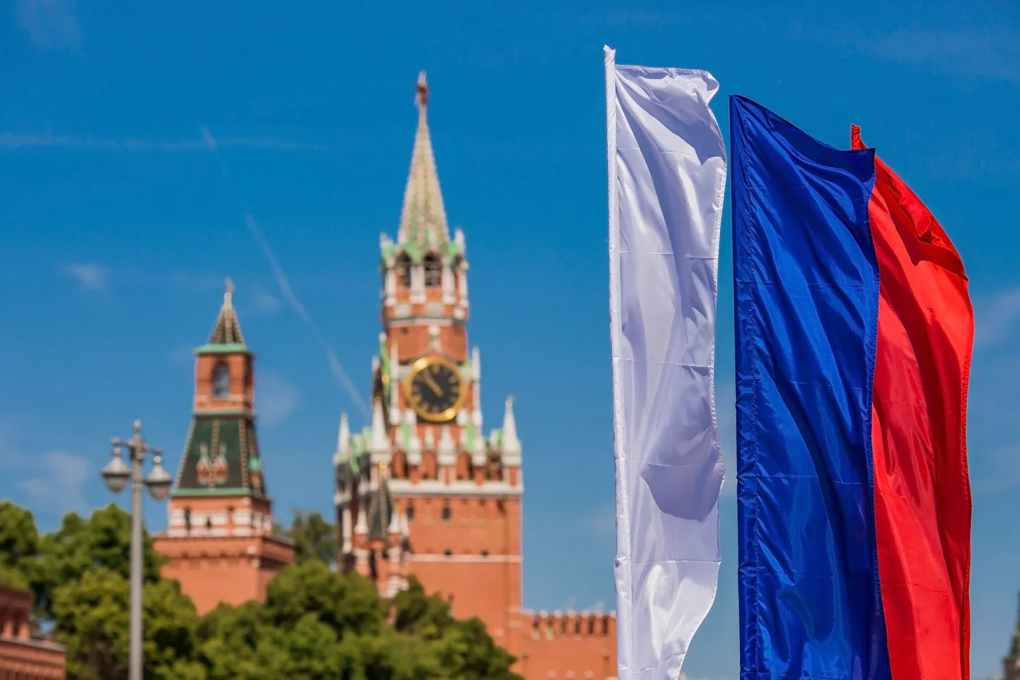 MOSCOW, RUSSIA - JUNE : The national flag of the Russian Federation against the background of the Kremlin's Spasskaya Tower on Red Square is the Russian Tricolor. The holiday is Russia Day.