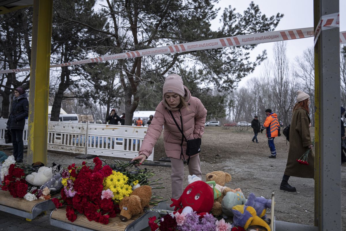 Женщина принесла цветы к автобусной останоке, на которой в результате российского ракетного удара погибли дети. Город Днепр, Украина. 16 января 2023 года.