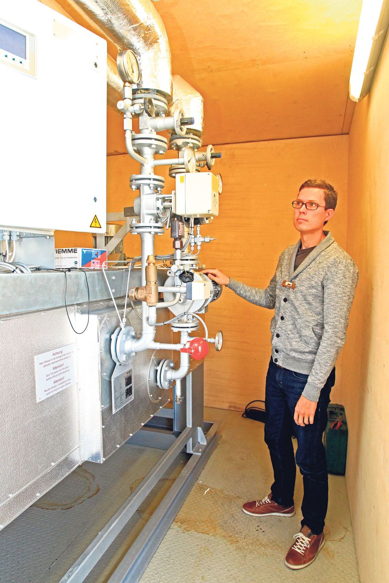 Kroonpressi keskkonnajuht Sander Jahilo näitab Saksamaalt tarnitud õhk-vesi-soojusvahetit, mille võimsusest piisab, et kütta suuremal osal aastast soojaks kõik ettevõtte ruumid.