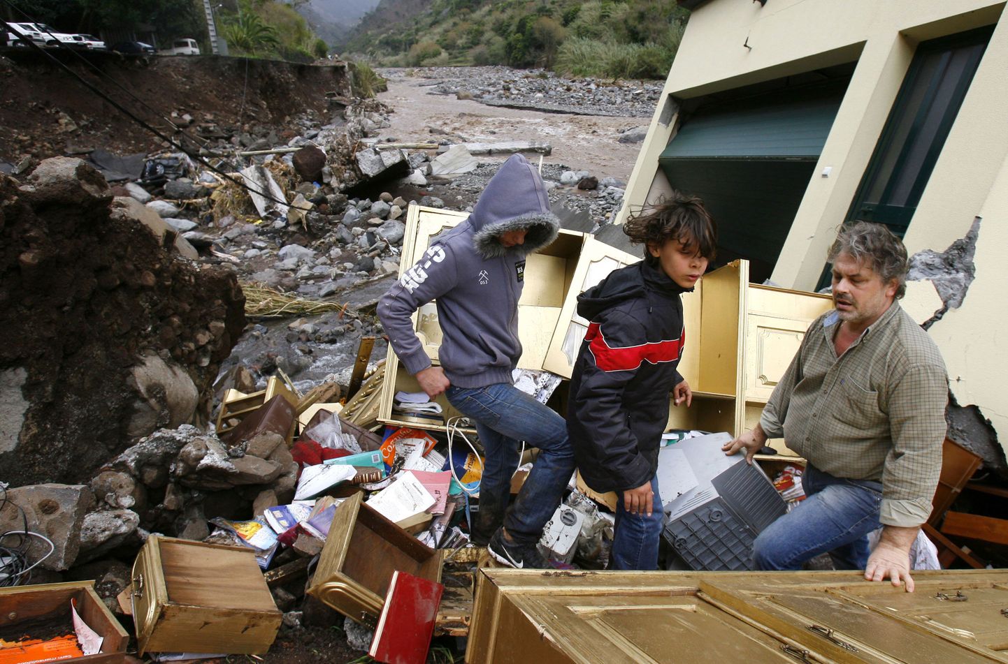 Mees koos oma lastega kodu jäänuste juures Madeiral Fuchnalis.