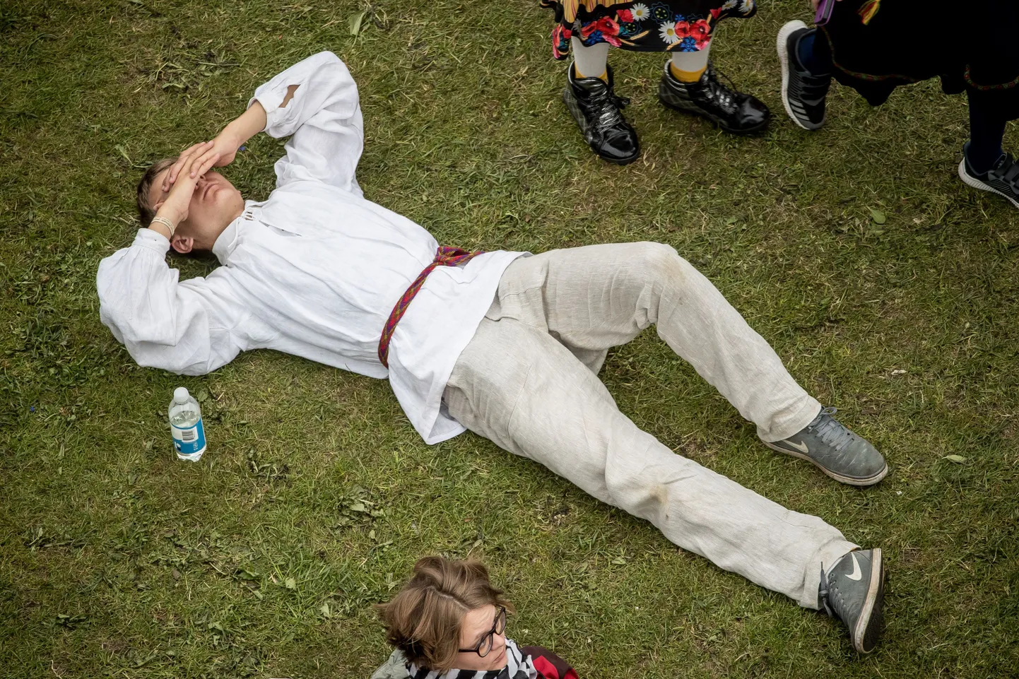 XII noorte laulu-ja tantsupidu. Lauluväljak. Peoline lamab murul selili.
