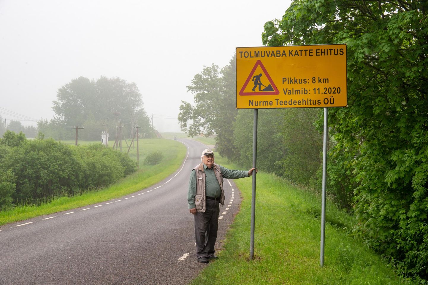 Ako Luts seisab Metsküla teel infotahvli juures, mis teatab tolmuvaba katte valmimisest.