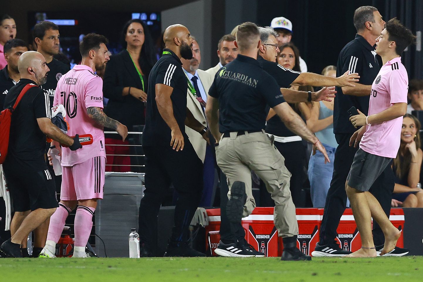 Fänn jooksmas Lionel Messi (vasakul) poole Miami Interi koduväljakul. Lisaks turvameestele seisab Messi ja fänni vahel tema ihukaitsja Yassine Chueko (keskel).