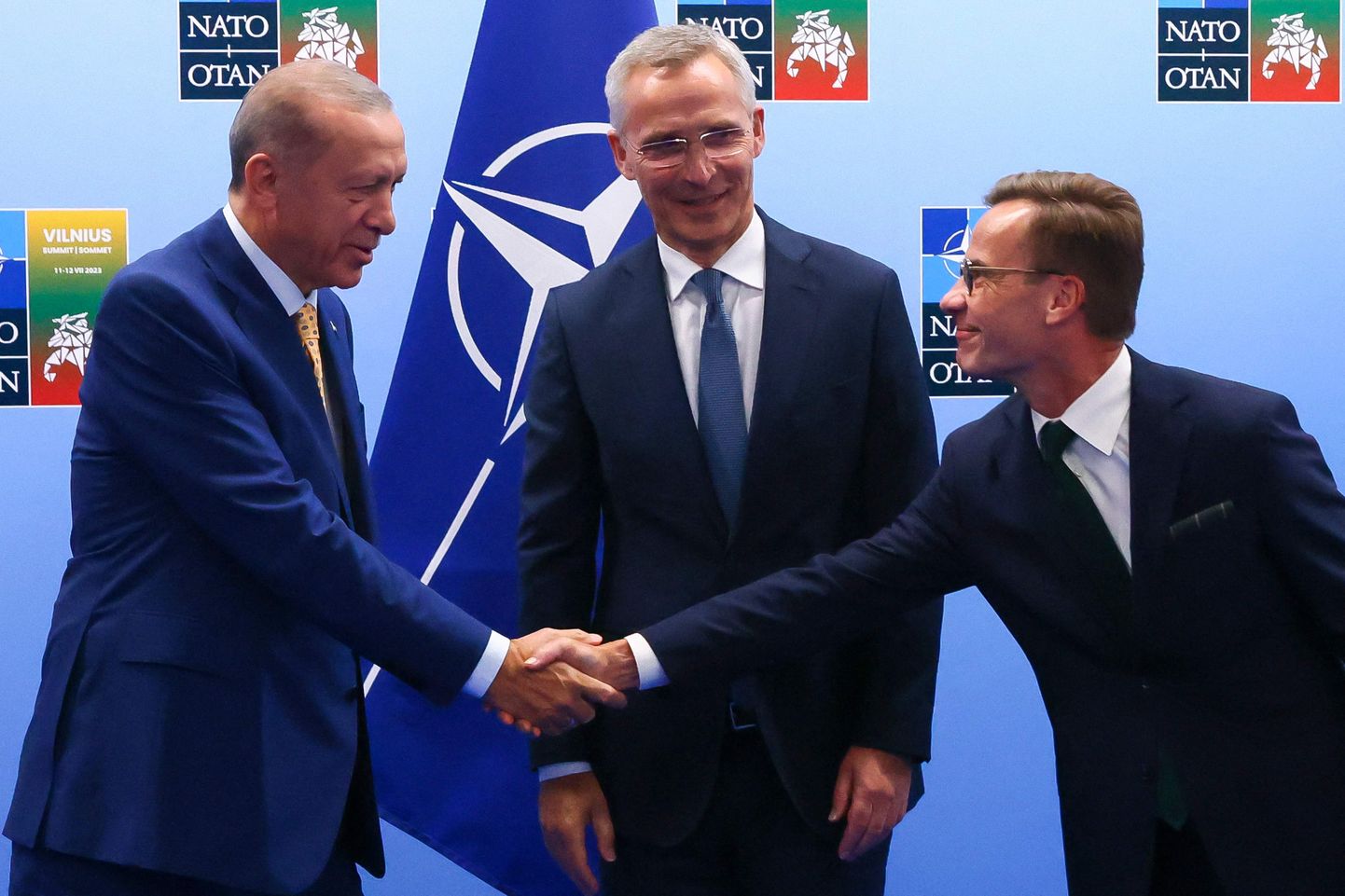 Президент Турции Тайип Эрдоган и премьер-министр Швеции Ульф Кристерссон пожимают друг другу руки перед генеральным секретарем НАТО Йенсом Столтенбергом.