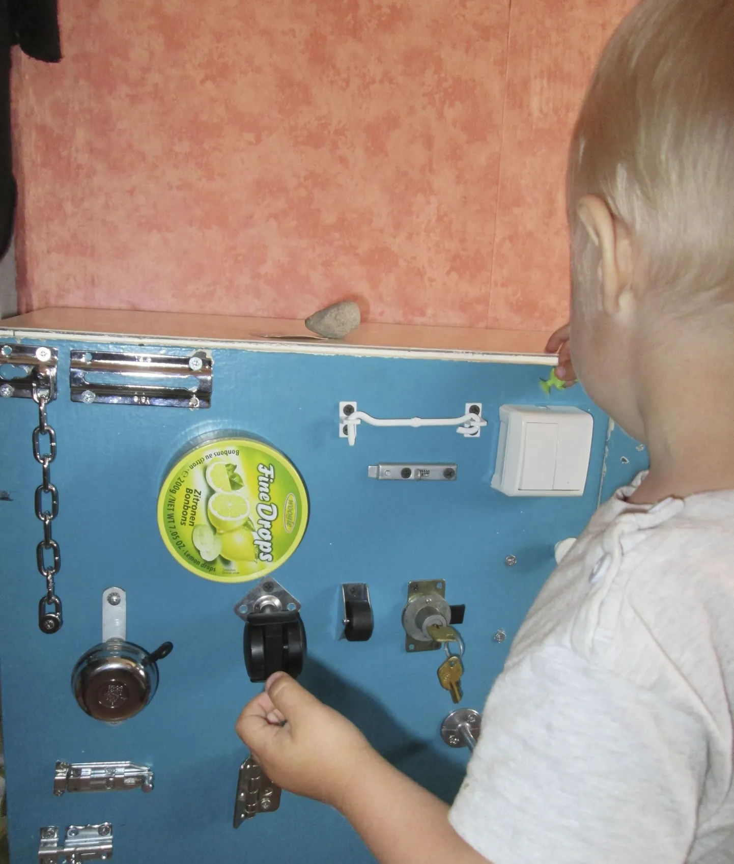 Sellel mängulaual ootavad väikest mängijat uksekett, haak, kahe klõpsuga lüliti, jalgrattakell, kaks eri suuruses diivanilaua ratast, lukusüdamik koos võtmega, kaks riivi ning plekist karbike. Enamik asju on kodusest majapidamisest taaskasutusele võetud, osa on ostetud ehituspoest.