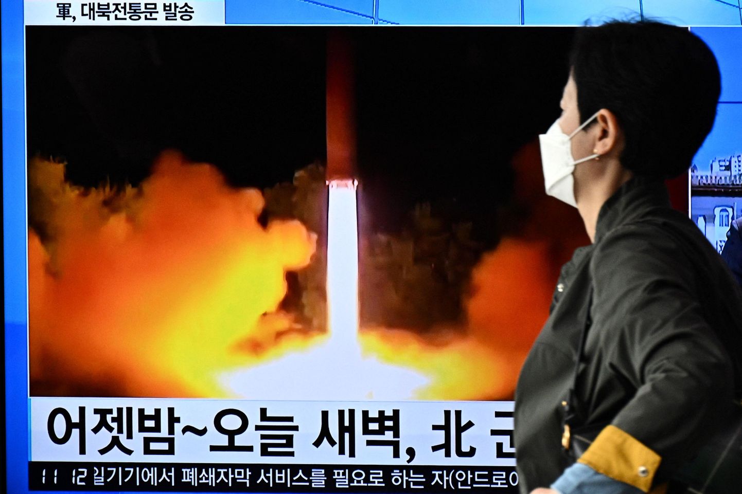 Souli elanik möödumas ekraanist, mis kuvab Põhja-Korea raketikatsetust.