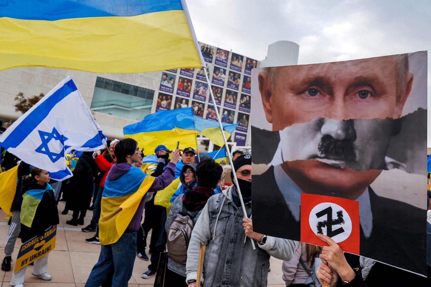 Plakat mullu märtsis Iisraelis Tel Avivis peetud meeleavaldusel Ukraina toetuseks: Vladimir Putini fotole on rebitud natsikurjategija Adolf Hitleri vuntsid, all Ukraina ründamise kahekordne Z-sümbol, mis meenutab natside haakristi.