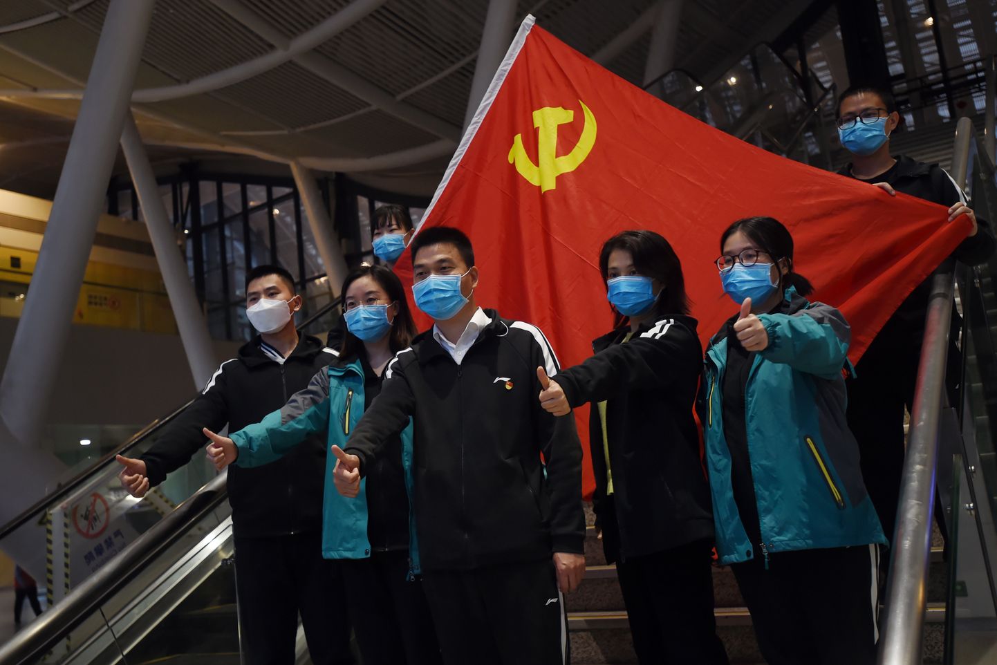 Uue koroonaviiruse epitsentrist Wuhanist lahkuvad arstid poseerimas Hiina kommunistliku partei lipu taustal. Kuna Wuhanis on uusi nakatunuid vähemaks jäänud, saavad paljud mujalt riigist appi saabunud meditsiinitöötajad tagasi koju minna.