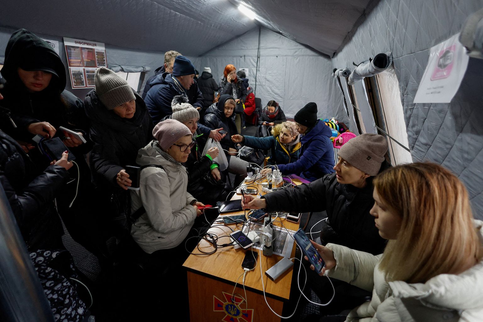 Украинцы заряжают мобильные гаджеты после российских бомбардировок гражданской инфраструктуры