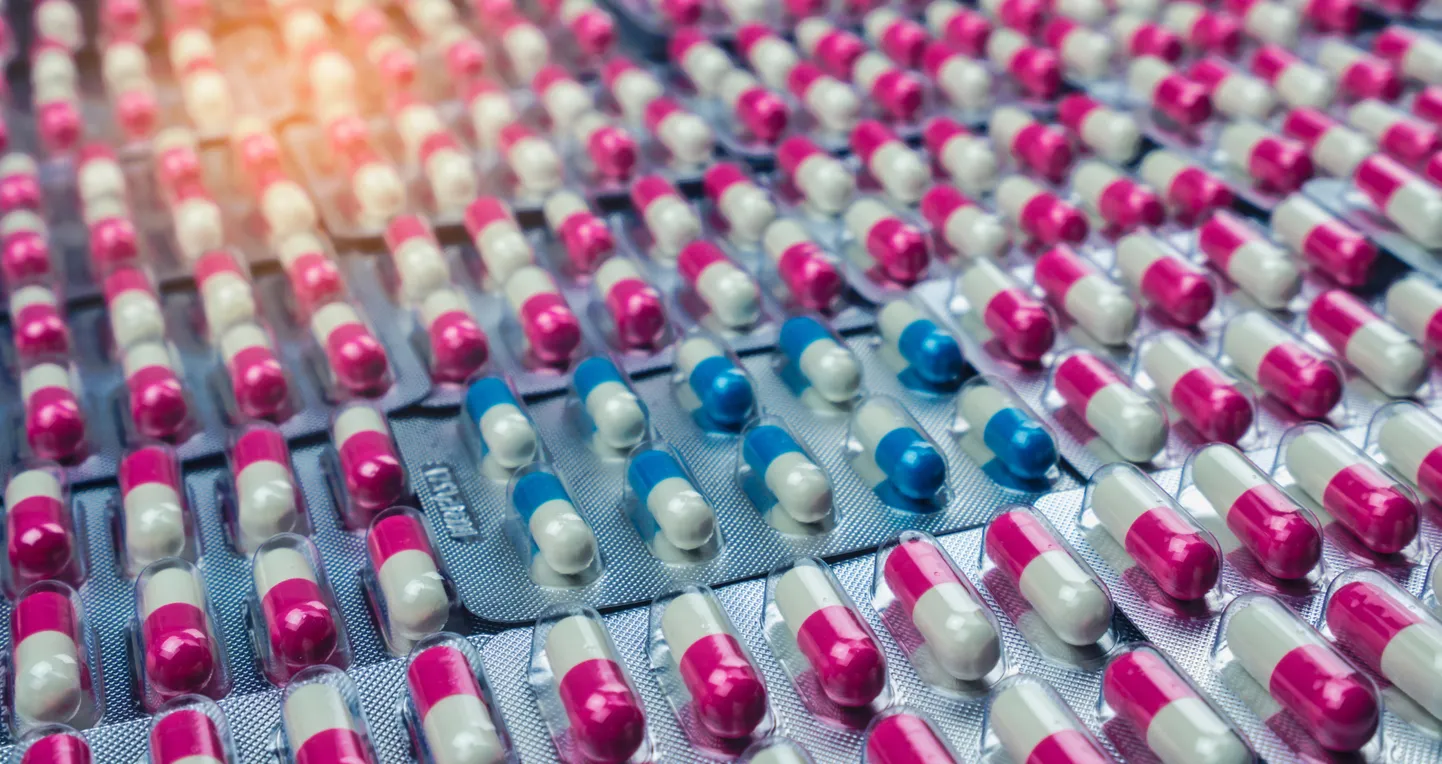 Closeup pink-white and blue-white antibiotics capsule pills in blister pack. Antimicrobial drug resistance. Pharmaceutical industry. Global healthcare. Pharmacy background. Amoxicillin capsule pills.