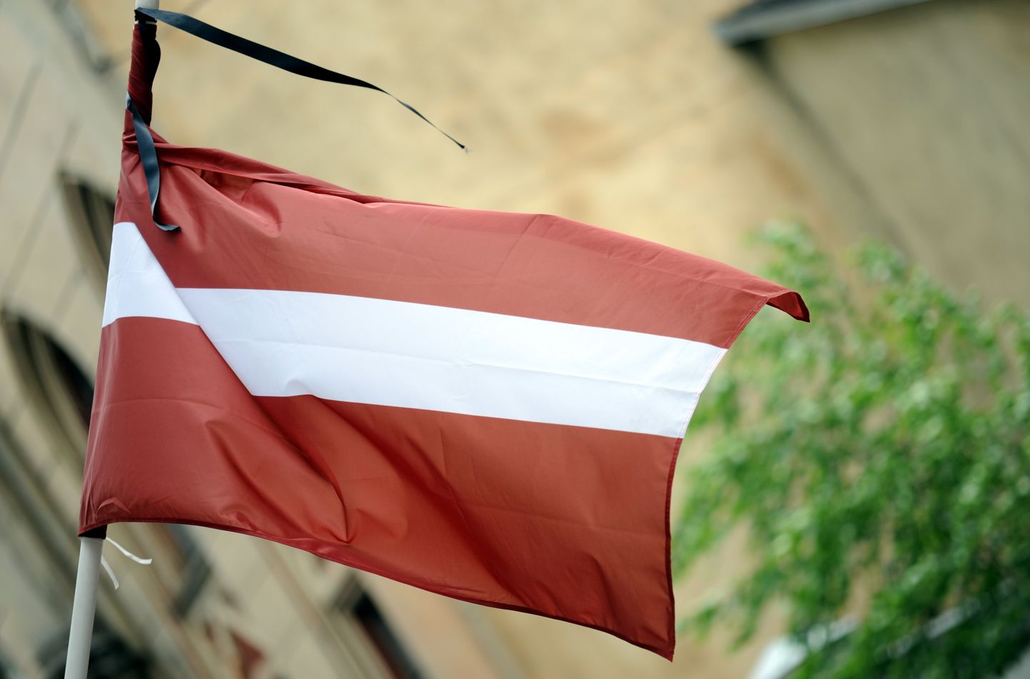 Latvijas karogs ar sēru lenti.