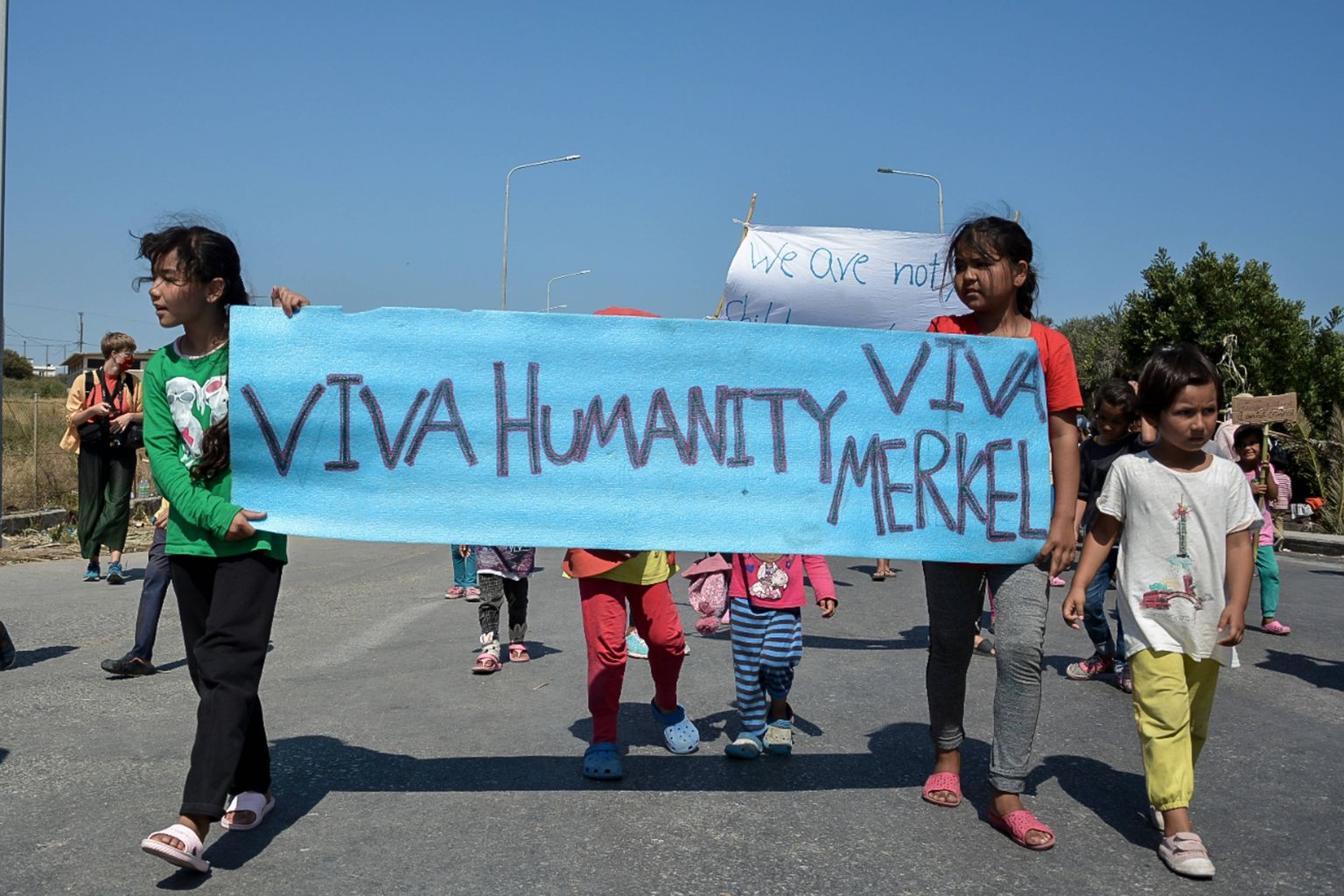 Moria põgenikelaagri põlengu järel peavarjuta jäänud migrandid plakatiga, millel kiri: «Elagu inimlikkus. Elagu Merkel.»