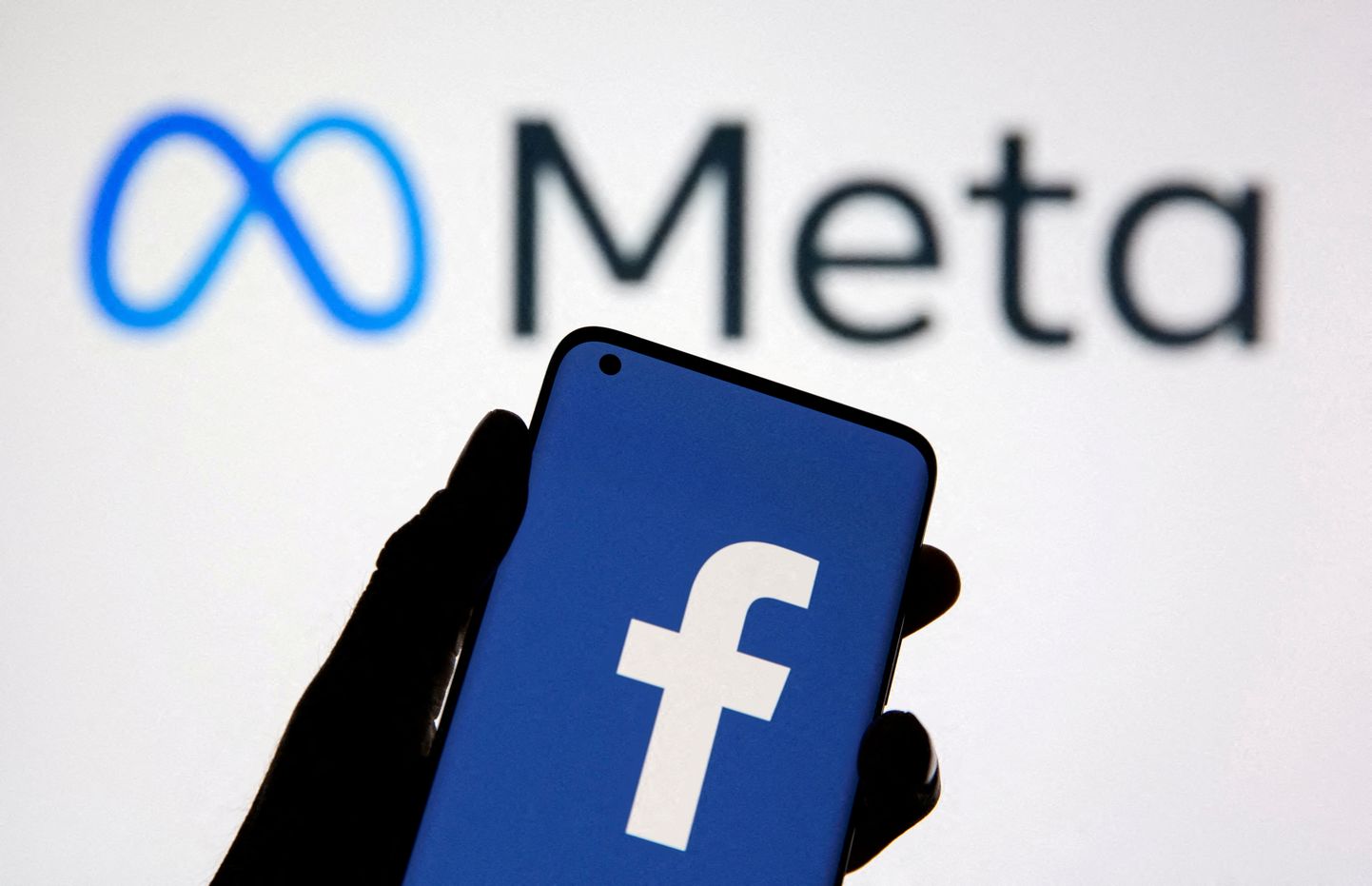 Nutitelefon Facebooki logoga, taustaks Meta logo. Foto on illustratiivne.