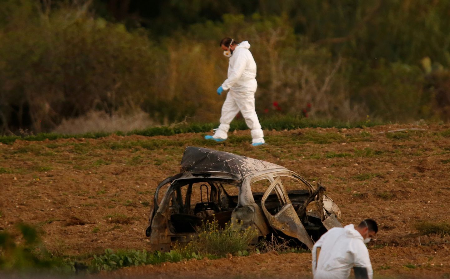 FILE PHOTO: Forensic experts walk in a field after a powerful bomb blew up a car (Foreground) and killed investigative journalist Daphne Caruana Galizia in Bidnija, Malta, October 16, 2017.   To match Special Report MALTA-DAPHNE/CHINA. REUTERS/Darrin Zammit Lupi/File Photo