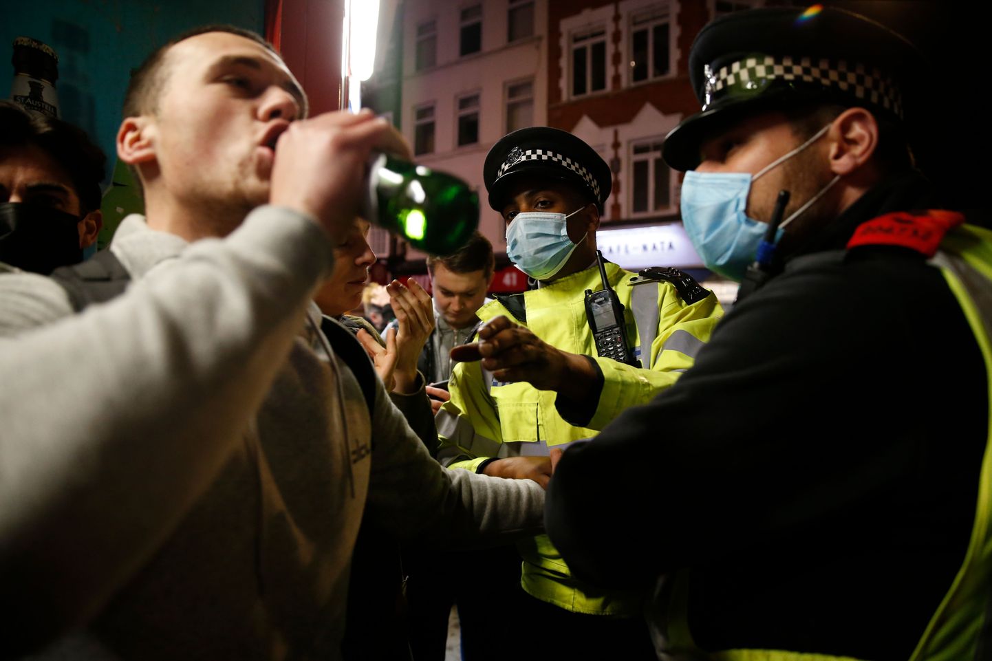 Londonlane teeb õllepudelile põhja peale enne, kui politsei koroonapiirangute tõttu inimesed laiali ajab.