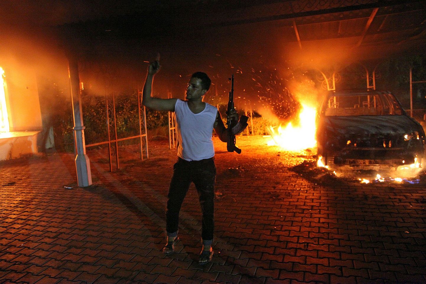 Relvastatud mees vibutab Banghazis tulirelva. Tema selga taga põlevad auto ja USA konsulaat.