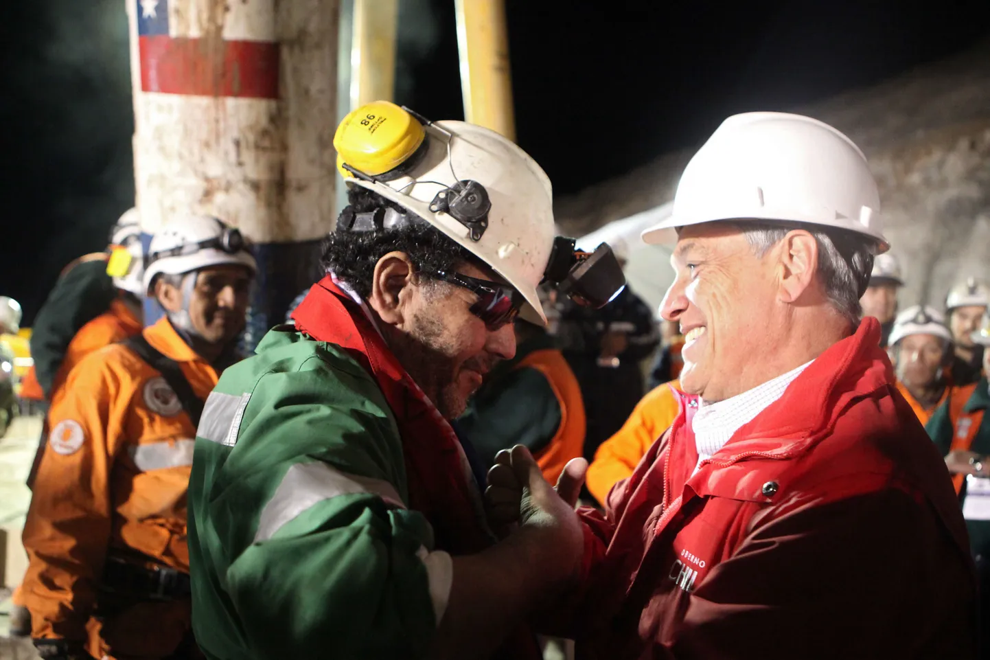 Президент Чили Себастьян Пинера приветствует последнего из спасенных шахтеров - Луиса Урсуа (слева).